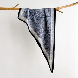 Detailed macro shot of vintage blue paisley silk scarf draped on a wooden branch