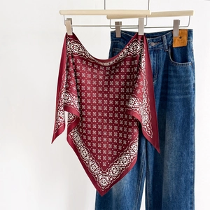 Vintage burgundy geometric silk scarf displayed on a wooden hanger with blue denim jeans