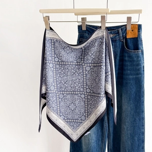 Blue paisley print triangular sun-protective silk scarf draped with denim on a hanger