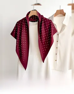Detail view of a wine red polka dot silk shawl draped elegantly on a white dress