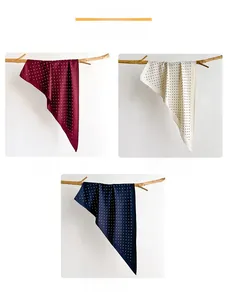 Detail view of polka dot silk scarves in burgundy, white, and navy blue on a wooden hanger