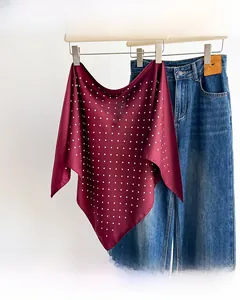 Close-up of lightweight burgundy polka dot silk scarf hanging on a wooden hanger
