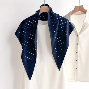 Elegant navy blue polka dot silk-like scarf draped on a white dress with wooden hanger