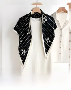 Detailed macro view of black triangle scarf with white floral embroidery and polka dots