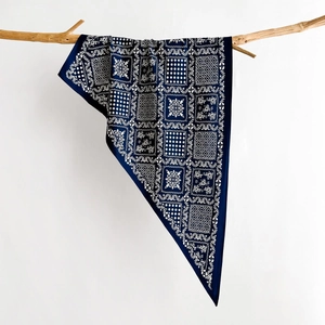 Detail of navy silk scarf with geometric floral print draped on a natural wooden branch