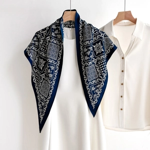 Navy blue bohemian print silk scarf draped over a white dress on a wooden hanger