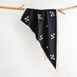 Retro black silk scarf with white polka dots and floral print hanging on a wooden branch