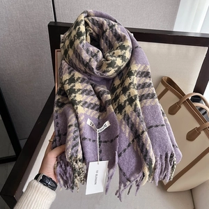 Macro view of purple houndstooth knit scarf texture with fringe detail and branded tag
