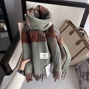 Close-up of houndstooth scarf texture with fringe details and woven brand label