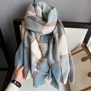 Close-up of thick plaid scarf with blue and beige blocks and fringed tassel edges
