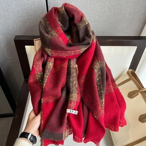 Detail of red and brown plaid scarf featuring soft knit texture and woven label