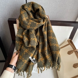 Detail of dark green and orange checkered scarf with tassels on a wooden chair