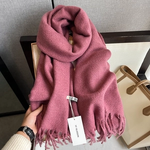 Detailed close-up of thick berry pink knit scarf with long fringe and textured fabric