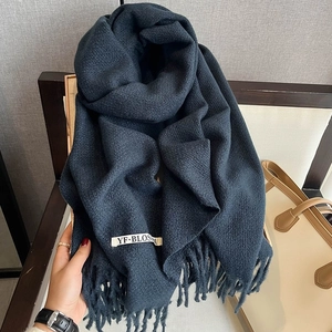 Detailed view of dark blue knit scarf with elegant fringe edges and brand logo tag