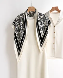 Close-up of black and white paisley print triangle scarf on a wooden hanger