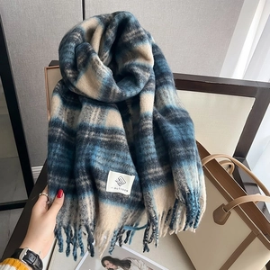 Close-up of thick blue plaid scarf texture with long twisted tassels and logo label