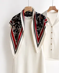 Detail of red and black paisley print silk scarf on a white dress for elegant styling