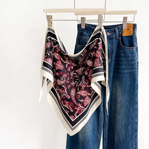 Classic paisley print silk scarf in black and red paired with blue jeans on a white hanger