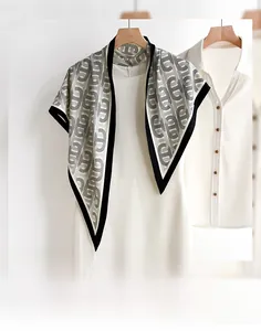 Detailed view of grey chain-print triangular silk scarf with black contrast hem on a white dress