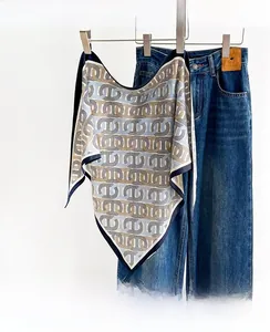 Close-up of silk-like scarf with classic chain print paired with dark blue denim jeans