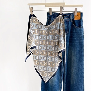 Elegant silk-like scarf with blue chain print on a wooden hanger with denim pants