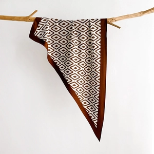 Silk-like geometric diamond print scarf draped on a branch for a minimalist style