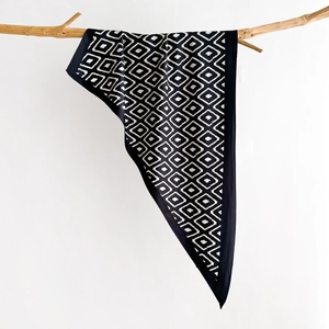 Close-up of silk scarf with geometric pattern hanging on a natural wooden branch