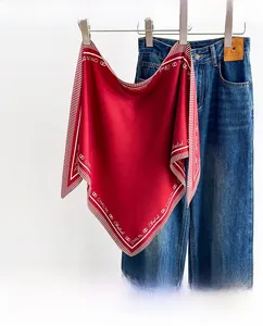 Detail view of red silk square scarf with geometric borders and classic logo print