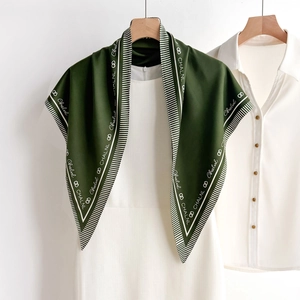 Classic dark green silk square scarf with white letter prints hanging on a white dress