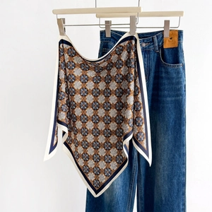 French vintage silk scarf with blue and orange geometric patterns hanging on denim