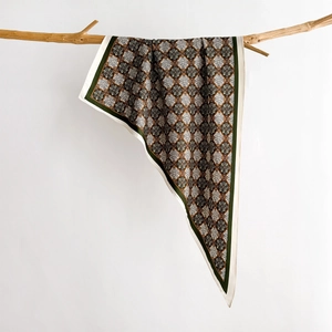 Detail of vintage French triangle scarf draped over a wooden branch on a white backdrop