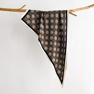 Detail of vintage geometric silk scarf hanging on a wooden branch with soft lighting