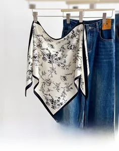 Detail of floral printed triangle scarf with black border and lightweight fabric