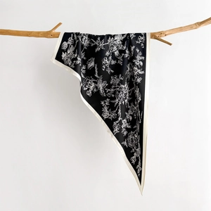 Detail of floral print silk scarf with hand-drawn botanical patterns on black background