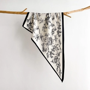 Elegant floral print silk scarf with bird motifs draped over a natural wooden branch