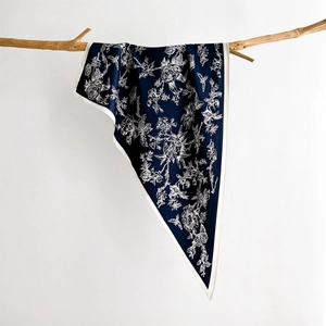Navy blue floral silk scarf with bird prints hanging on a natural wooden branch