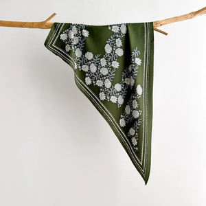 Elegant dark green silk scarf with white floral print hanging on a rustic branch