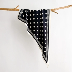 Polka dot neck scarf in black and white hanging on a natural wooden branch display