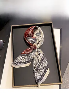 Dettaglio di sciarpa in 100% seta di gelso con motivi paisley e fermaglio di perle eleganti