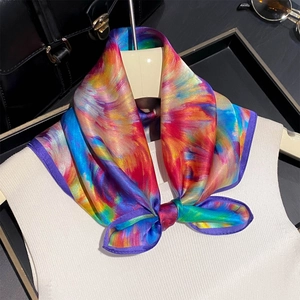 Silk square scarf with abstract colorful print tied in a bow on a white outfit