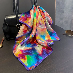 Silk square scarf with colorful abstract print and purple border draped on leather bag