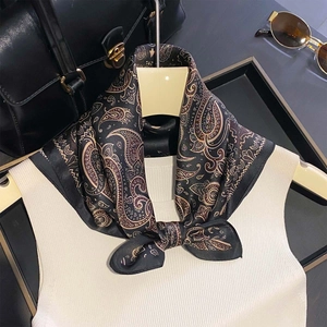 Elegant paisley silk scarf in black and gold tied on a mannequin with fashion accessories