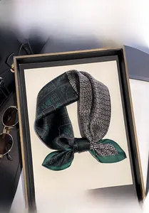 Detail of 100% mulberry silk scarf featuring green paisley and geometric patterns
