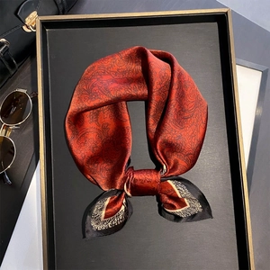 Sciarpa di seta rossa con motivi paisley neri su elegante vassoio nero e oro