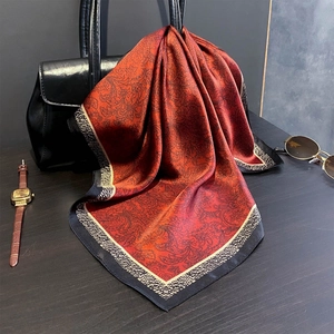 Elegante sciarpa in seta paisley rosso-marrone drappeggiata su borsa in pelle