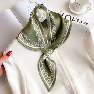 Dark green silk neck scarf with white spiral pattern tied on a white shirt with camellia