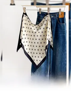 Detailed macro of a cream polka dot silk triangular scarf hanging on a wooden hanger
