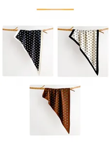 Detailed display of polka dot silk scarves in black, white, and caramel brown on branches