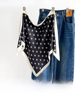 Detailed close-up of polka dot pattern on a soft silk scarf paired with blue denim jeans