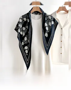 Detail of floral printed silk shawl on a wooden hanger against a white background